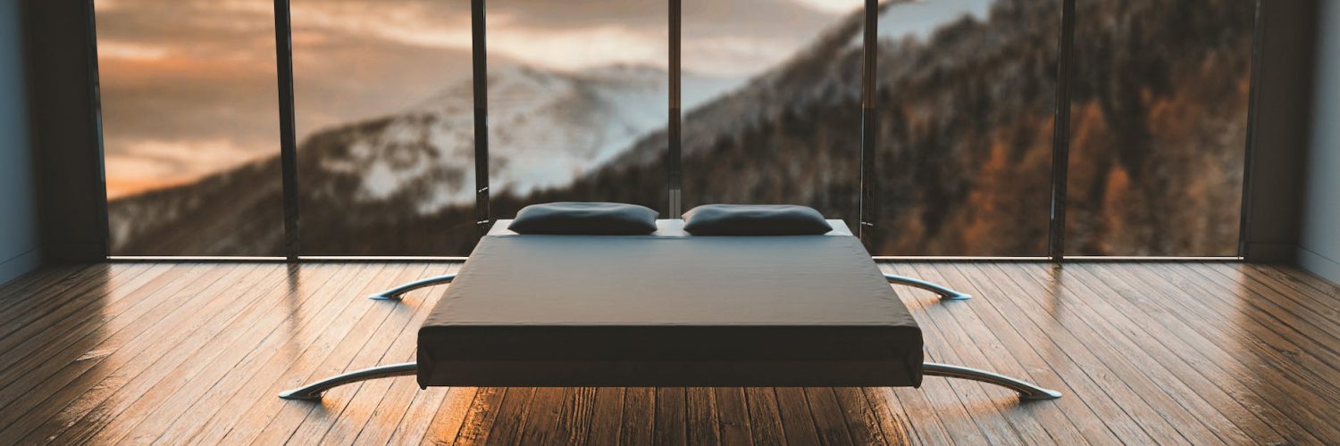 black mattress in front of a large window behind a mountain