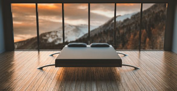 black mattress in front of a large window behind a mountain