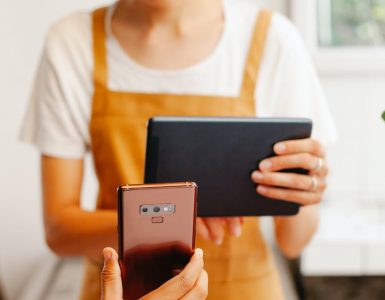 crop worker with tablet against partner with smartphone in cafe