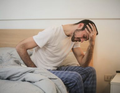 young man in sleepwear suffering from headache in morning