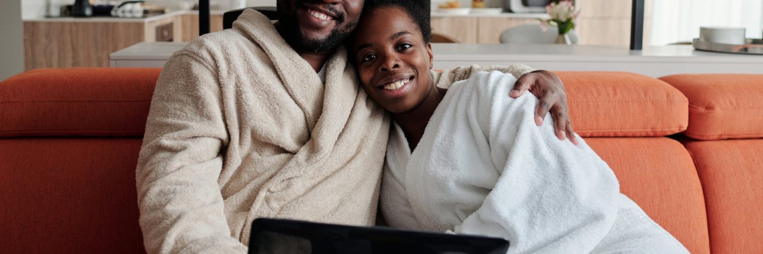 a man and woman in white bath robe sitting on orange couch