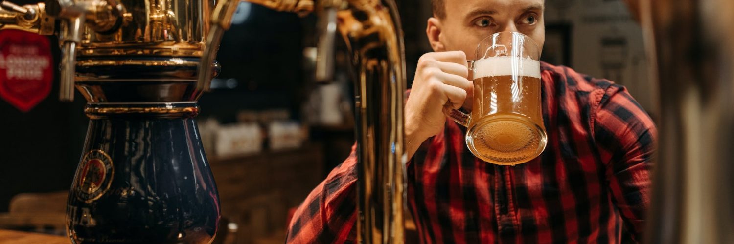 a man in plaid long sleeves drinking beer